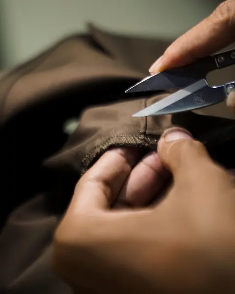 Penjahit merapikan benang dengan gunting kecil