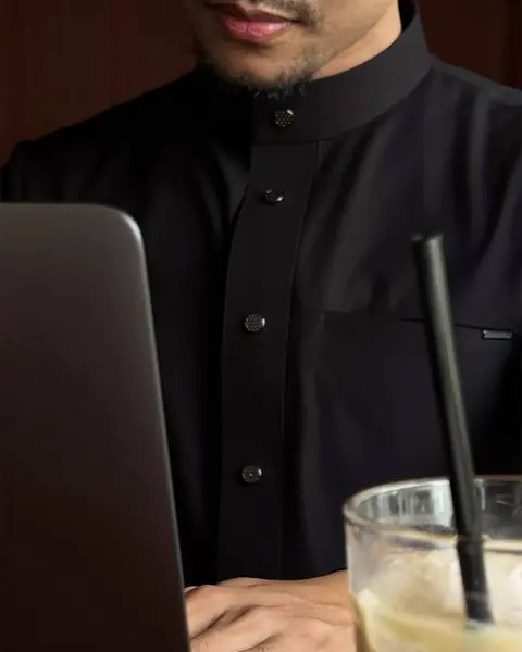 Thobe hitam berkancing dipakai bekerja di depan laptop